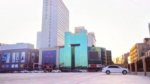Een moderne straat in de stad met een hoog gebouw met een glazen gevel die reflecteert en een bord met Chinese karakters.