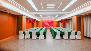 Een congrescentrum met rijen tafels en stoelen, een rode banner en een modern plafondontwerp.