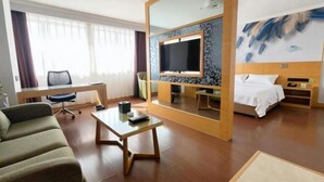 Een hotelkamer met een bed, een bureau, een stoel, een televisie en een grote spiegel.