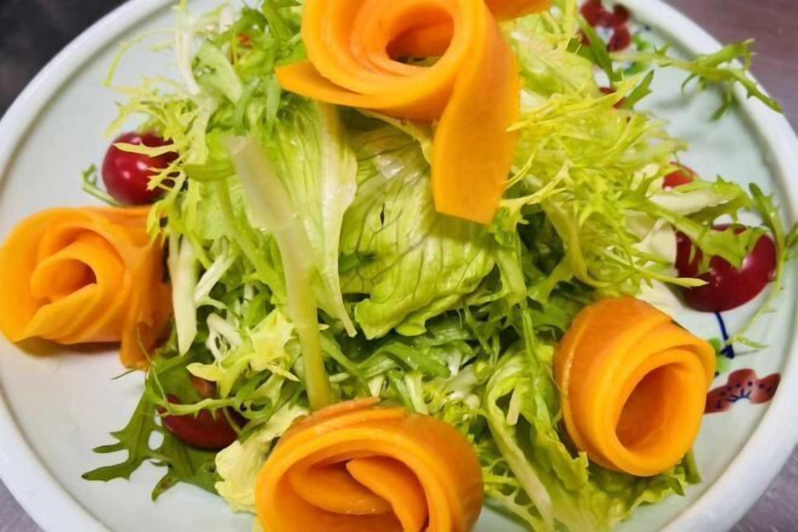 A salad with lettuce and carrot flowers on a plate.