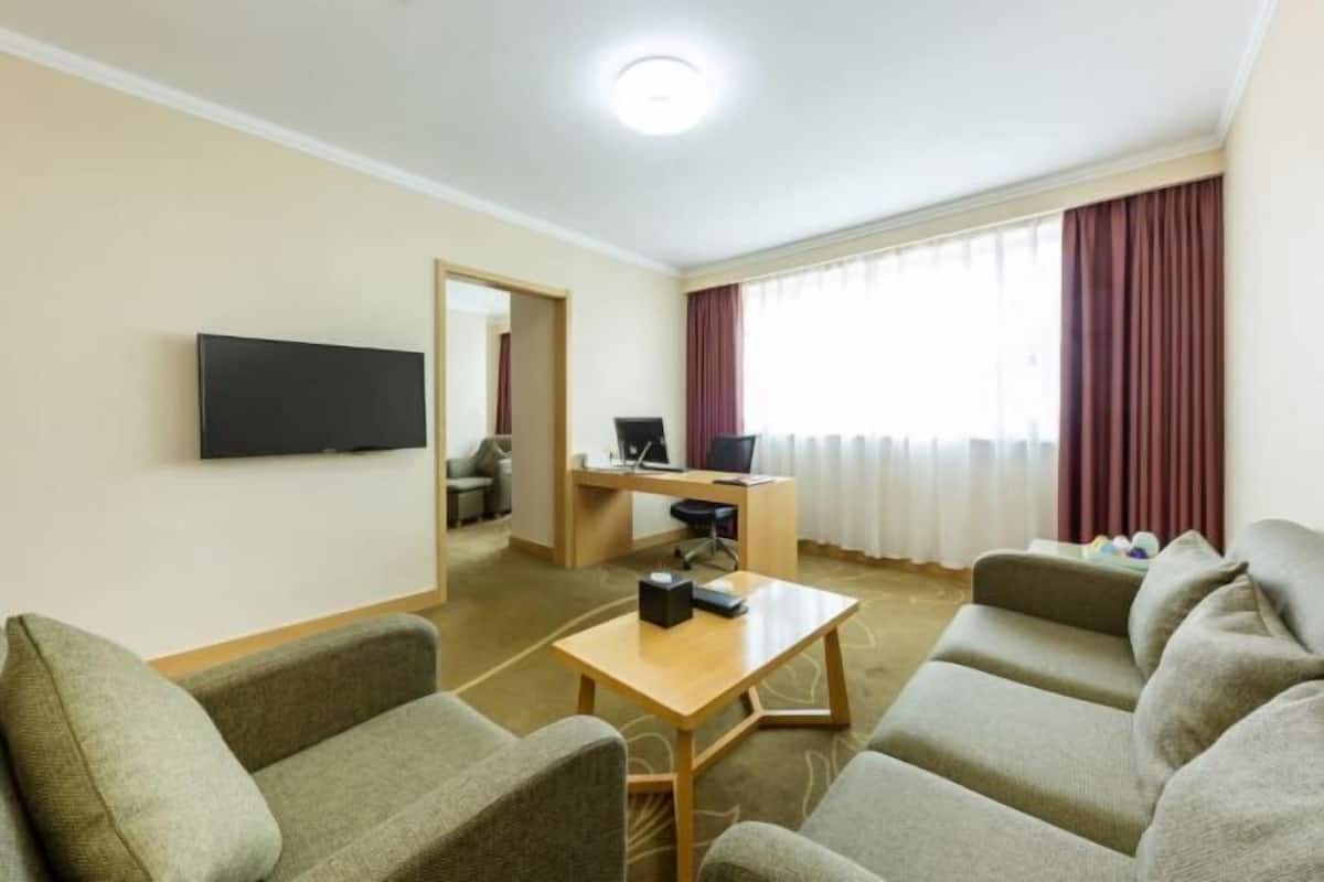 Habitación de hotel con televisión de pantalla plana, escritorio con computadora, sofá y una pequeña mesa.