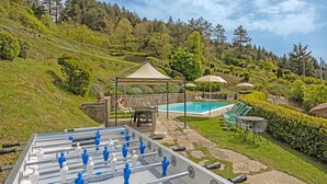 A pool area with a foosball table, lounge chairs, and umbrellas. - Villa in Cortona with 3 bedrooms sleeps 6 (Cortona)