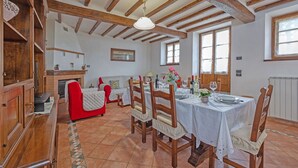 A dining area with wooden beams, a fireplace, and a table set for a meal. - Villa in Cortona with 3 bedrooms sleeps 6 (Cortona)