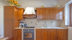 A kitchen with wooden cabinets, a stove, a sink, and a backsplash. - Villa in Cortona with 2 bedrooms sleeps 4 (Cortona)