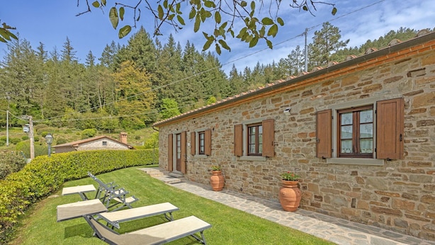 A stone building with wooden shutters, a paved patio, and a lawn with outdoor furniture. - Villa in Cortona with 2 bedrooms sleeps 4 (Cortona)