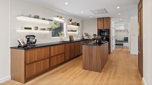 Eine moderne Küche mit Holzausstattung, einer schwarzen Arbeitsplatte und eingebauten Regalen.