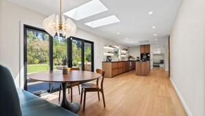 Eine moderne Küche mit Holzausbau, einer zentralen Kochinsel und einem Essbereich mit rundem Tisch und Stühlen.