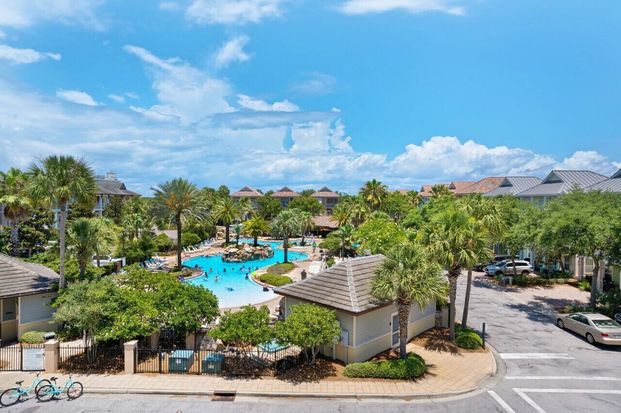 A resort with multiple swimming pools, palm trees, and a clear blue sky.