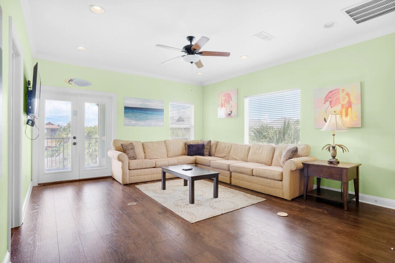Un salon avec un canapé d’angle beige, une table basse et un ventilateur de plafond.