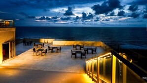 Eine Dachterrasse mit Tischen und Stühlen mit Blick auf das Meer.