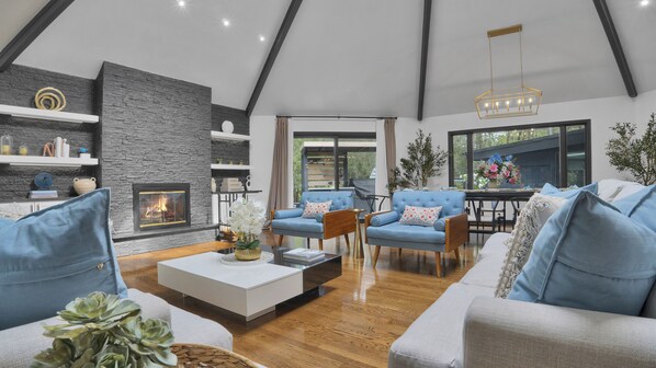 A modern living room with a fireplace, blue sofas, and a wooden coffee table.