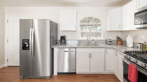A modern kitchen with stainless steel appliances, white cabinetry, and a window with a view. - Fab 2B/2Bth, All New  & Easy Access  to US99 (Fresno)
