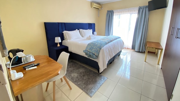 Habitación de hotel con cama, mesita de noche, lámpara y escritorio con silla.