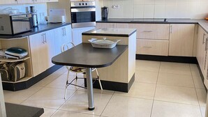 Una cocina moderna con alacenas de madera clara, encimera negra y una isla central con fregadero.