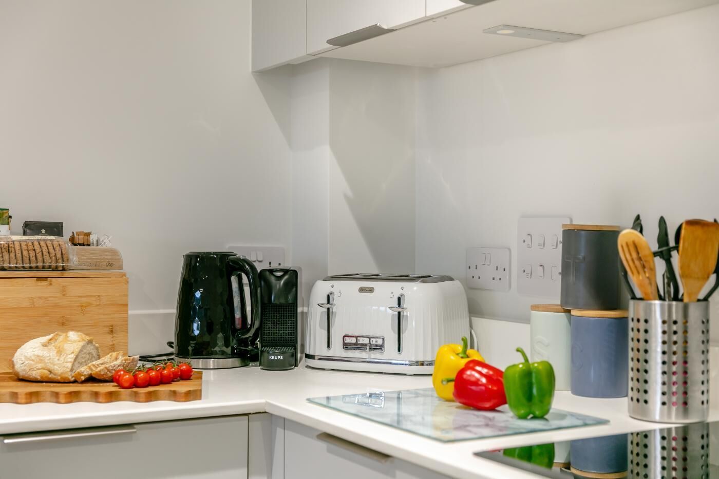 A modern kitchen with a toaster, coffee maker, and fresh vegetables on the counter.