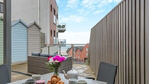 A balcony with a table set for breakfast, including croissants, a teapot, and cups. - 2 Bed in Woolacombe (oc-c29617) (Woolacombe)