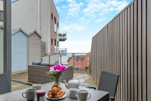A balcony with a table set for breakfast, including croissants, a teapot, and cups. - 2 Bed in Woolacombe (oc-c29617) (Woolacombe)