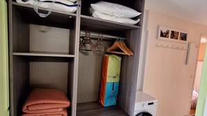 A laundry room with a washing machine, a shelf with folded towels, and a bag hanging on a hook. - T2 apartment with sea view and private parking in Cap Esterel vacation village (Saint-Raphaël)