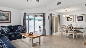 Een woonkamer met een bank, salontafel en een eethoek met stoelen en een tafel.