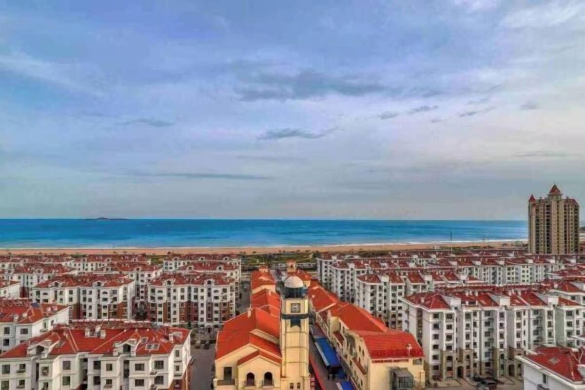 Ein Hotel an der Küste mit mehreren Gebäuden mit roten Dächern, einem zentralen Gebäude mit einem Uhrturm und Blick auf den Strand.