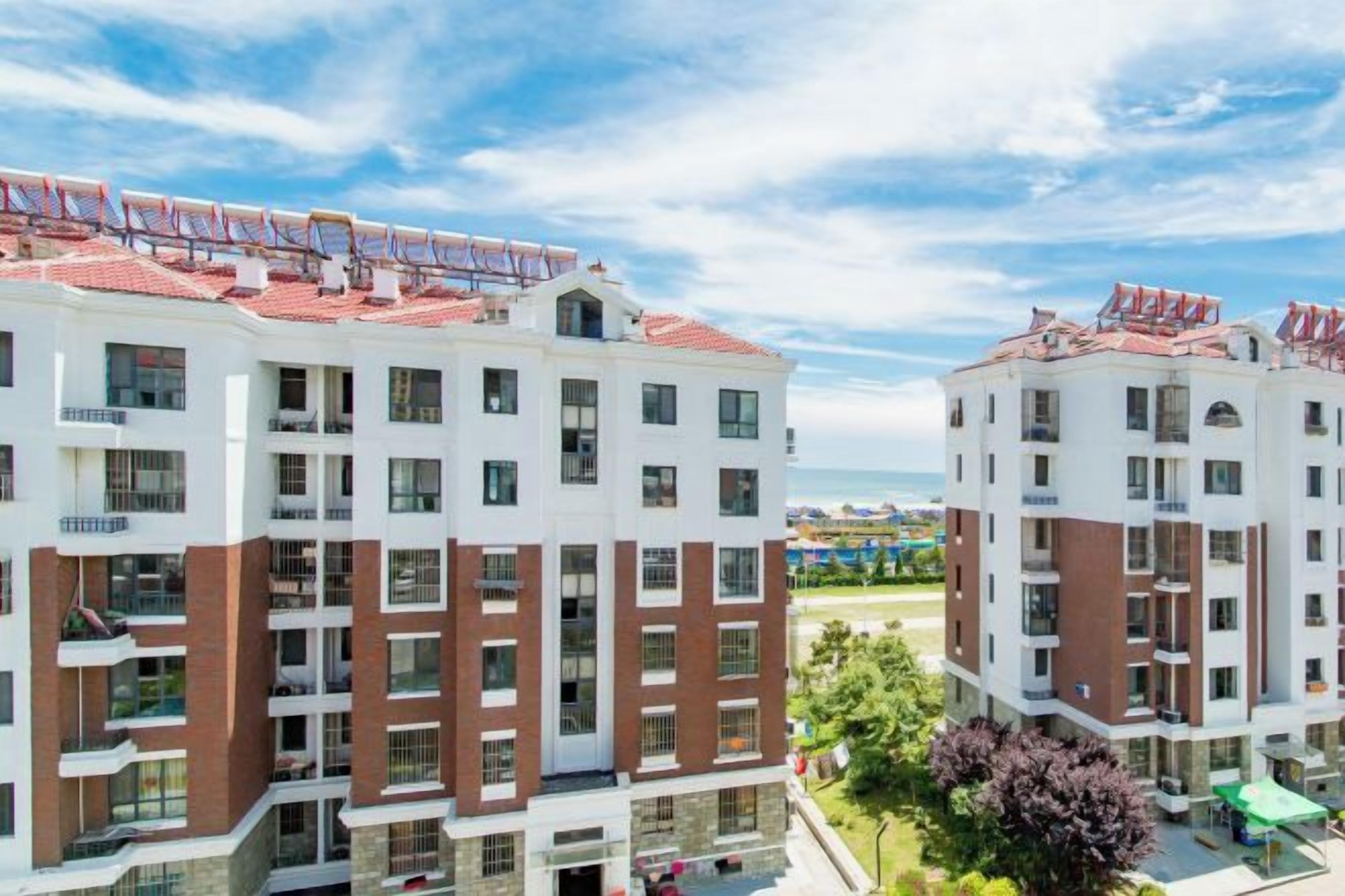 A multi-story hotel with balconies, a pool area, and a view of the beach.