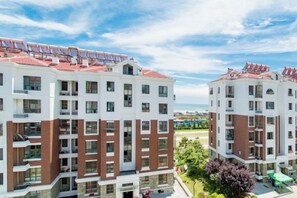 Ein mehrstöckiges Hotel mit Balkonen, einem Poolbereich und Blick auf den Strand.