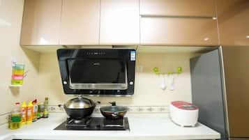 A kitchen with a microwave, stove, and a red appliance on the counter.