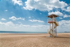 Ein Rettungsturm am Strand bei blauem Himmel.