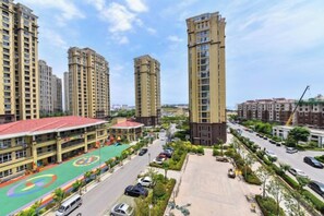 Een hoog appartementencomplex met meerdere verdiepingen, een parkeerplaats en een sportveld.