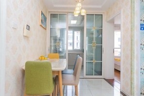 Un comedor con una mesa, sillas y un mantel verde. Hay dos lámparas sobre la mesa.