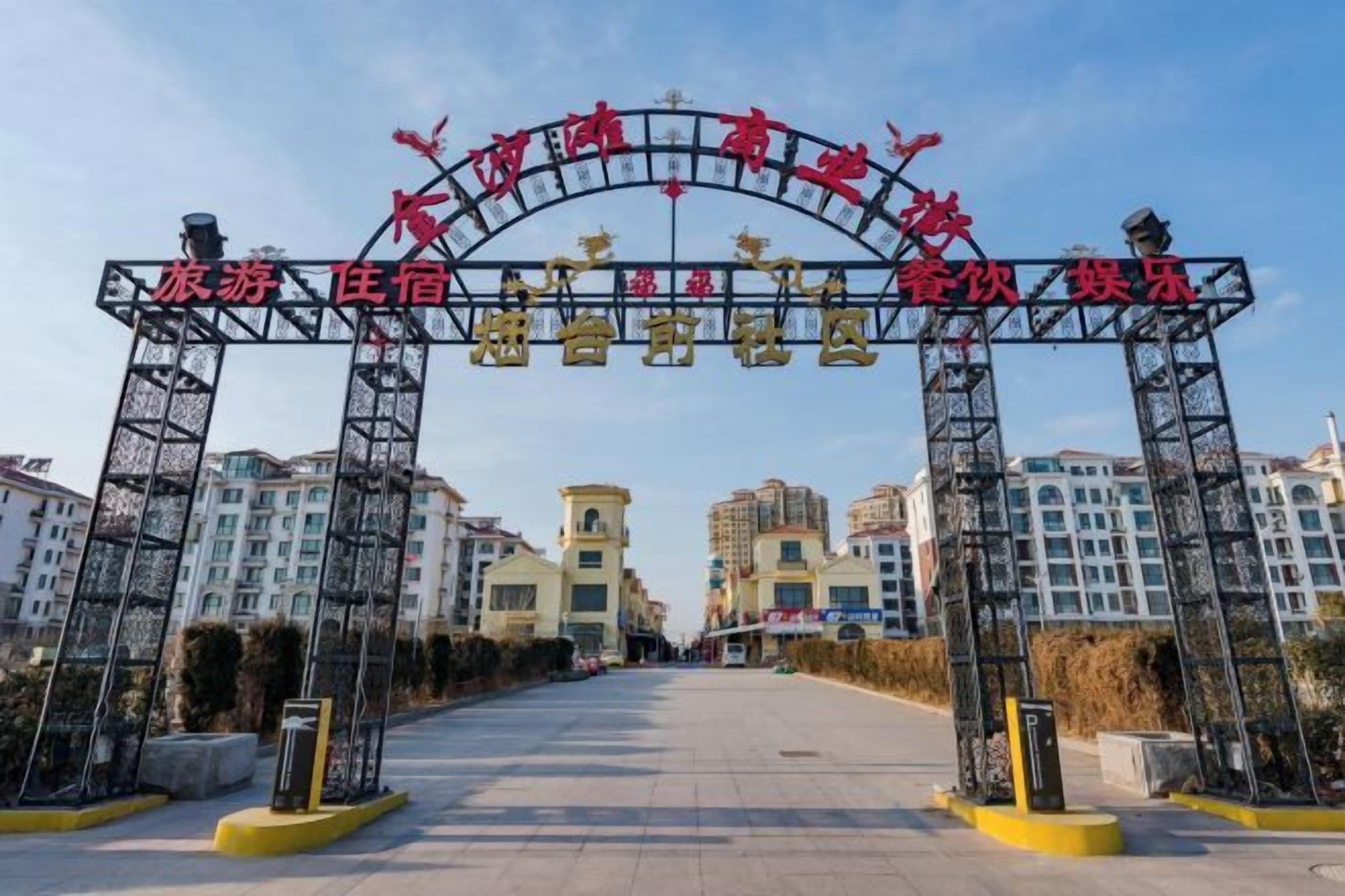A hotel entrance with a large archway, multiple floors, and a clear sky.