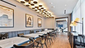Un restaurant moderne avec de longues tables communes et des banquettes, des œuvres d’art encadrées aux murs et un plancher en bois.