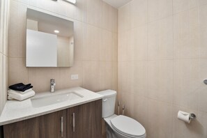 A modern bathroom with a white sink, a mirror, and a toilet.