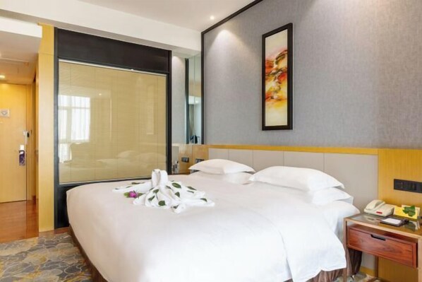 A hotel room with a bed, bedside table, and a painting on the wall.