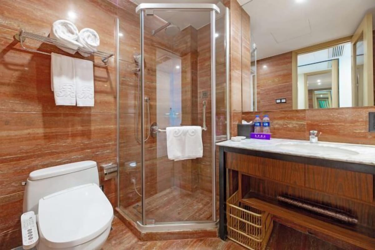 A modern bathroom with a glass-enclosed shower, a white toilet, and a vanity with a mirror.