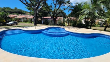 Una piscina con bordo curvo, circondata da un solarium in cemento.