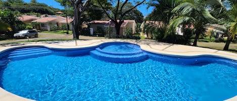 A swimming pool with a curved edge, surrounded by a concrete deck.
