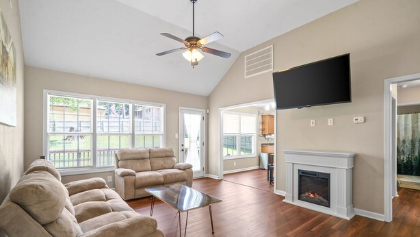 A spacious living room with a fireplace, a ceiling fan, and a large window. - Spacious 4-bedroom House near Downtown Clarksville (Clarksville)
