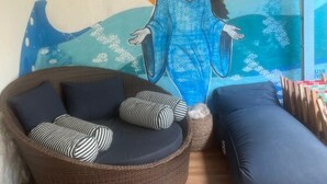 Ein Zimmer mit Wandgemälde, Korbmöbeln und einem blauen Kissen.