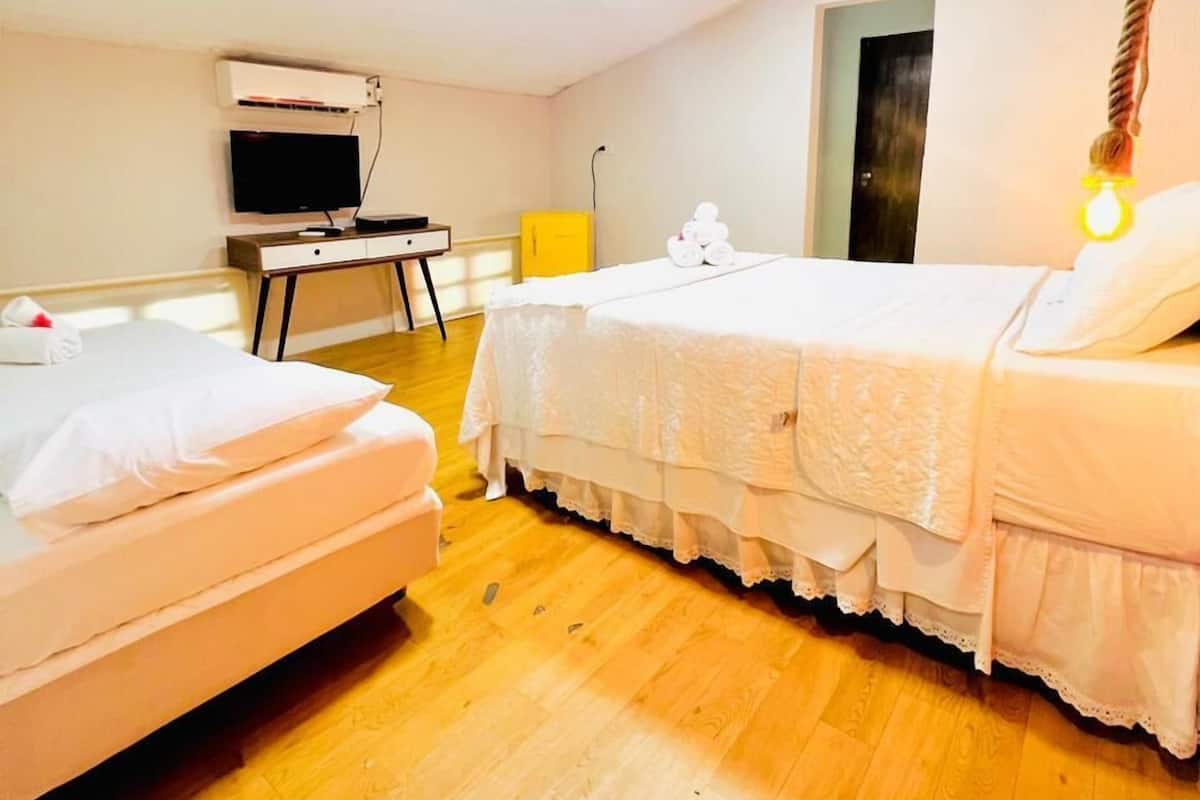 Ein Hotelzimmer mit zwei Betten, einem Fernseher und einer Deckenleuchte.