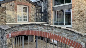 A stone house with a brick archway and a metal gate.