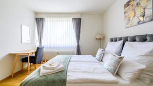 A hotel room with a bed, a desk, and a chair. - Marllon Suites – St. Alban Apartments – Apartment Arnold (Basel)