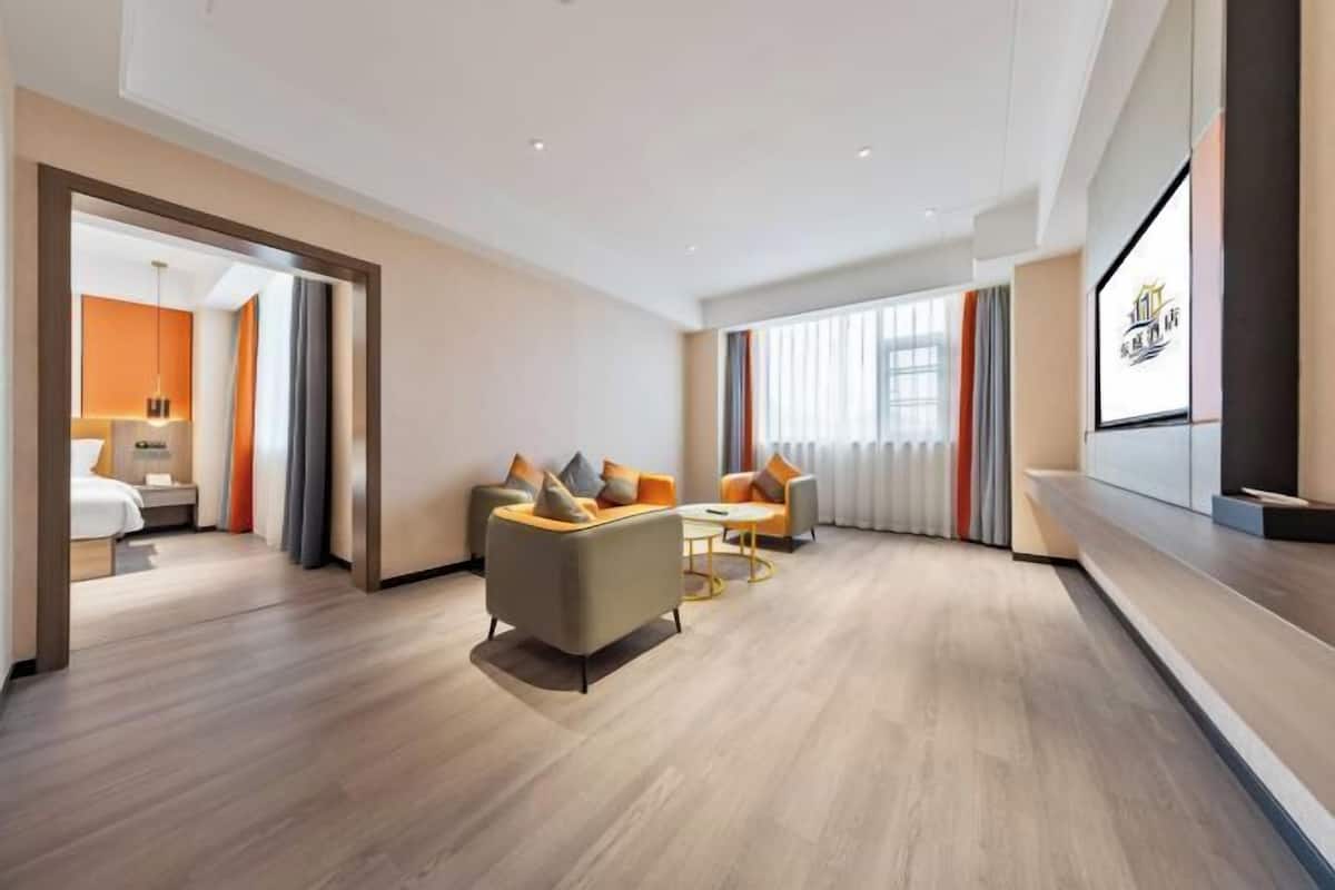 A modern hotel room with a sofa set, a small table, and a TV mounted on the wall.