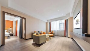 Una habitación de hotel moderna con un conjunto de sofá, una mesita y un televisor montado en la pared.