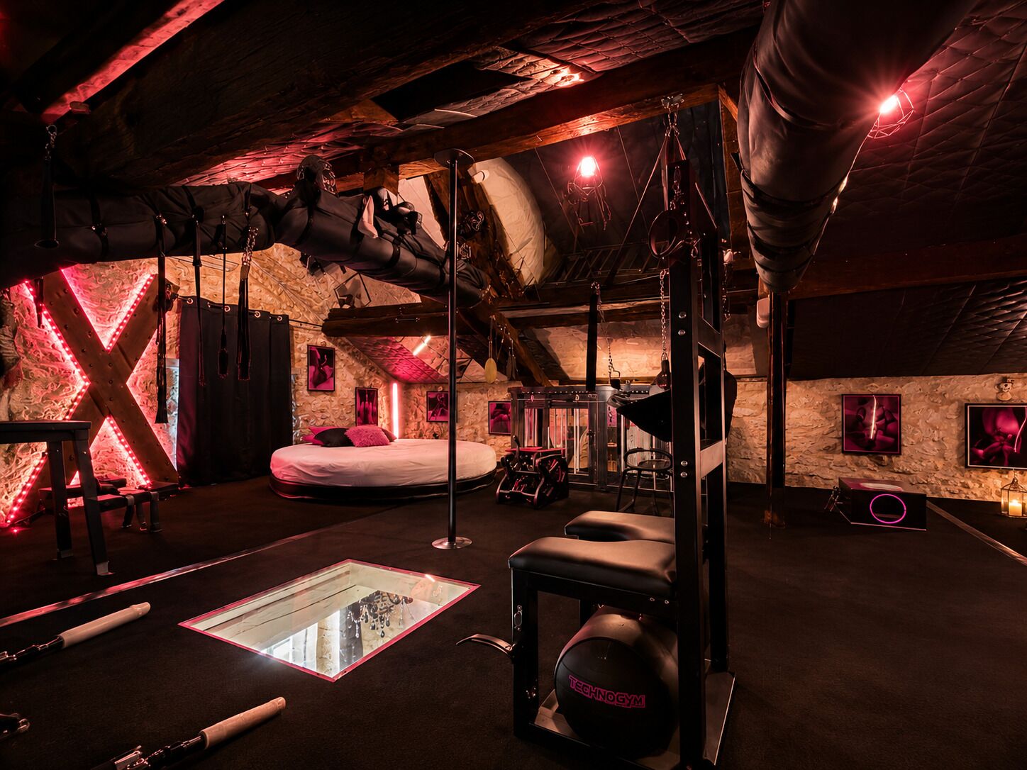 A gym with a bed, exercise equipment, and a large X-shaped light fixture.