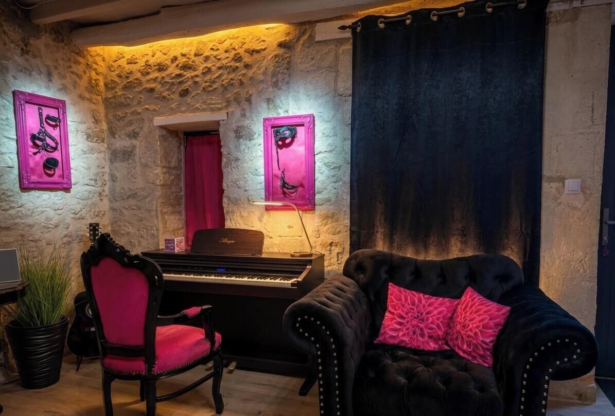A room with a piano, a plush sofa, and a stone wall.