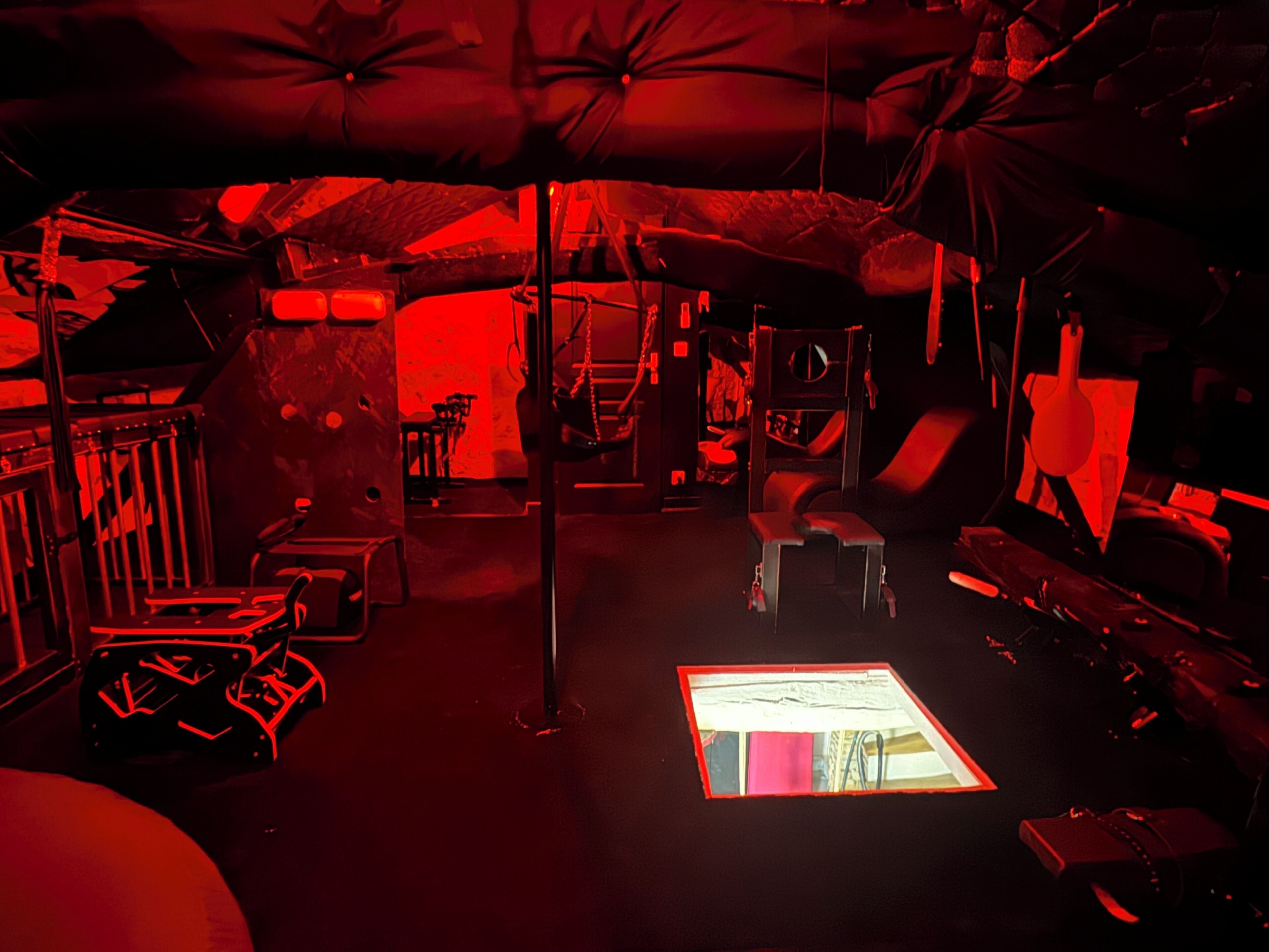 A dimly lit room with a central table, a chair, and a small window.