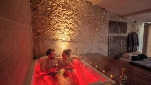 A stone-walled room with a hot tub, candles, and a bottle of wine on a tray. - Caporizon-love House-une Maison Entiere Dédiée aux Plaisirs de L'amour (Biras)