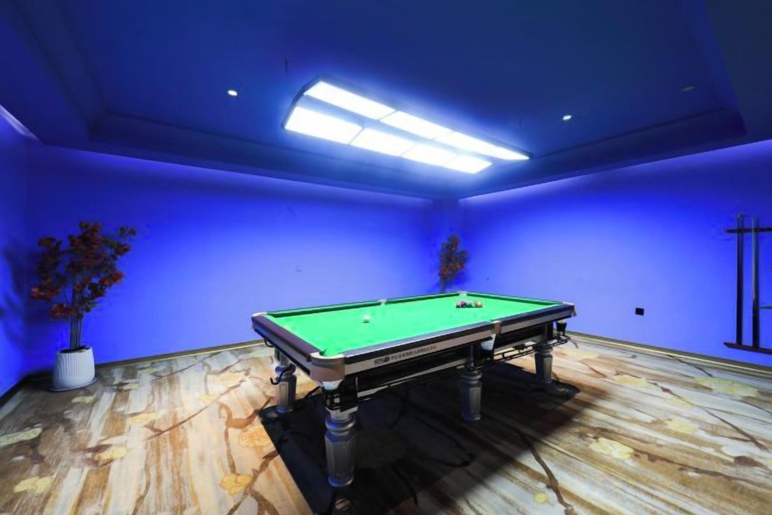 Une table de billard dans une pièce aux murs bleus et au plancher en bois.