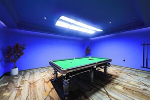 A pool table in a room with blue walls and wooden flooring.